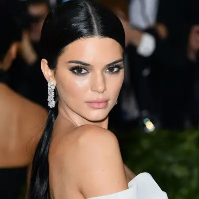Kendall Jenner wears a sleek, long middle-part ponytail and diamond earrings