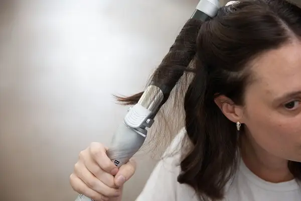 Hand curling long dark hair with the Beachwaver Co. Beachwaver Pro 1