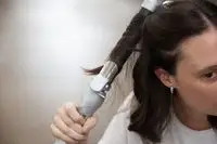 Hand curling long dark hair with the Beachwaver Co. Beachwaver Pro 1