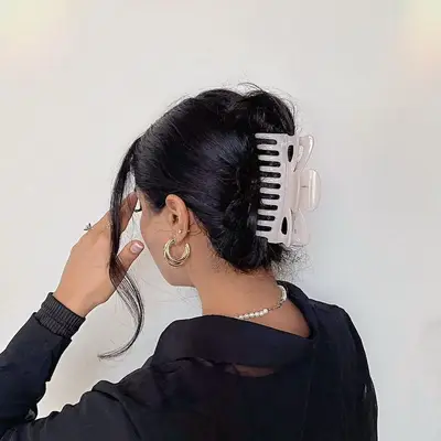 Back view of a French twist hairstyle with large white claw clip and face-framing tendril