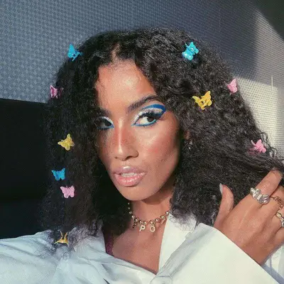 Beauty creator Nawel wears blue graphic eyeliner and natural curls with butterfly claw clips