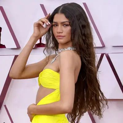 Zendaya wears long, wavy hair with a center part