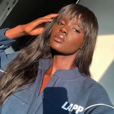 Duckie Thot wears long, wavy hair with brow-skimming bangs