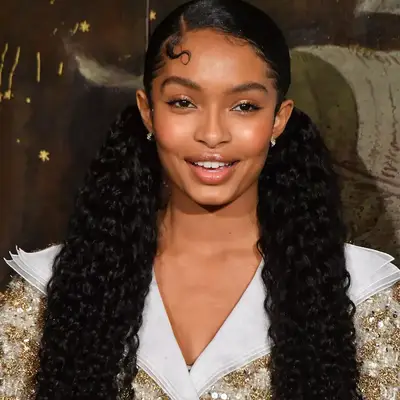 Yara Shahidi wears long, low curly pigtails with slick baby hairs