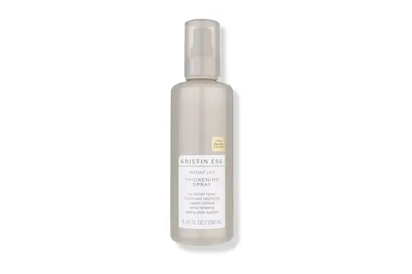 A person putting Oribe Maximista Thickening Spray in their palm