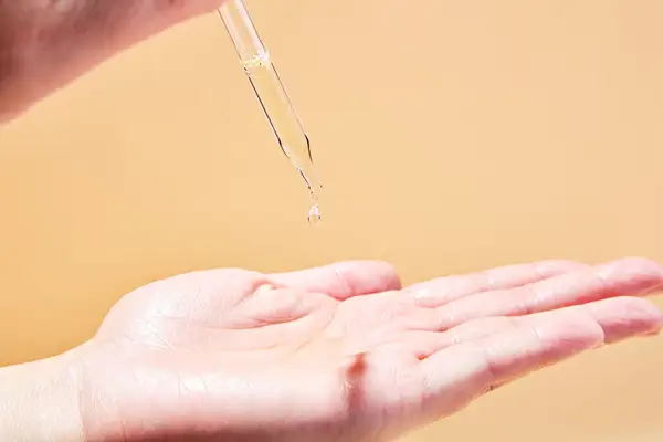 A person dripping Mielle Organics Rosemary Mint Scalp & Hair Strengthening Oil into their palm