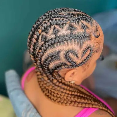 Black and copper red goddess braids with intricate heart designs at the scalp