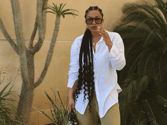 Tyla Lauren with goddess braids standing by a palm tree in Palm Springs