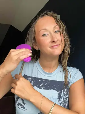 A person brushes their hair using the Wet Brush Original Detangler Hair Brush
