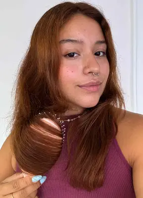 A person uses the Dae Vegan Detangle + Style Brush on their hair