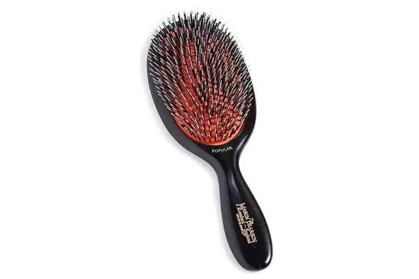 A person uses the Dae Vegan Detangle + Style Brush to brush their hair