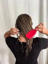 A person brushes their hair with the Tangle Teezer The Ultimate Detangler
