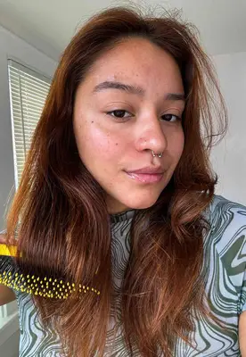 A person brushes their hair using the Drybar Super Lemon Drop Daily Detangler Brush