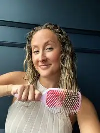 A person uses the Denman D38 The Detangling & Styling Paddle on their curly hair