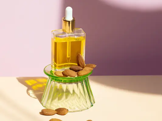 bottle of almond oil on tan counter against purple background
