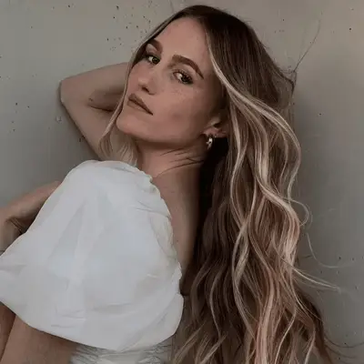 Model with long and wavy money piece blonde hair.