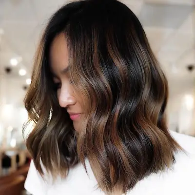 Close up of a person with dark hair and caramel highlights