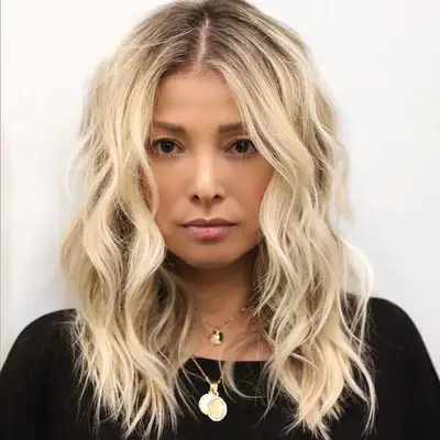 Person with soft blonde waves with a shadow root 