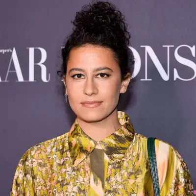 Ilana Glazer with curly bun on top of head and patterned button up shirt