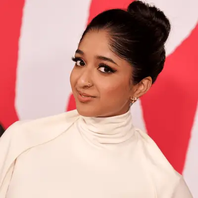 Maitreyi Ramakrishnan with white long sleeve high neck dress and slicked-back bun on top of head