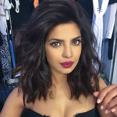 Priyanka Chopra posing with dark brown wavy medium length hair with purple lips