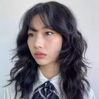 Asian model looking to the side with black choppy haircut with wispy bangs