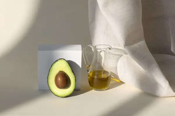 avocado on tan background next to olive oil