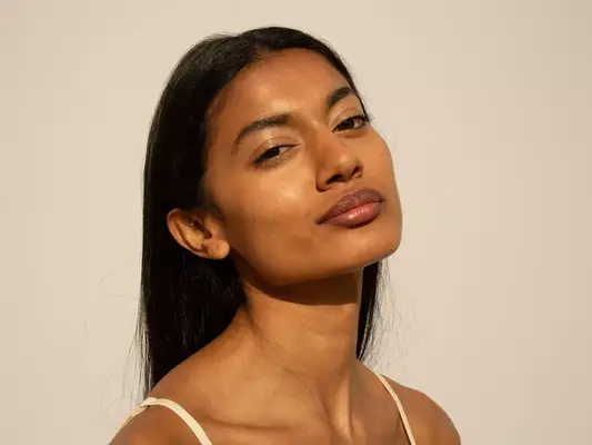 woman with long brown hair against tan background