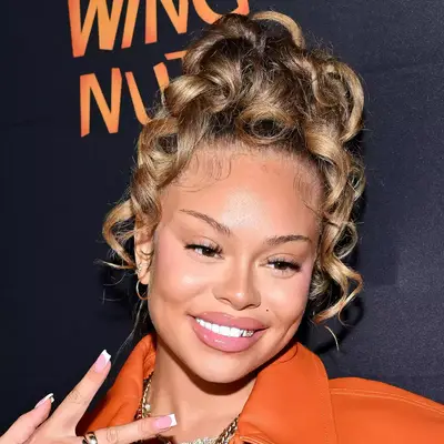 Latto with bronde hair, curled in messy bun on top of head