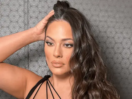 ashley graham running hand through long wavy hair