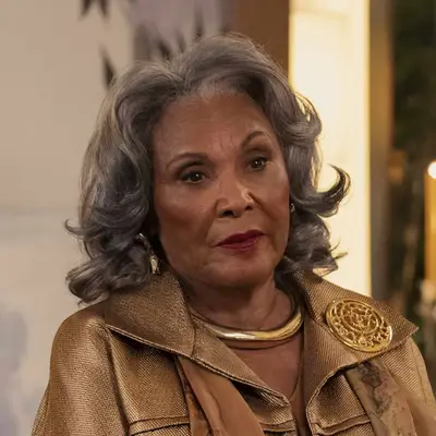 Pat Bowie with silver hair wearing a garment with a decorative brooch