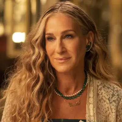 Sarah Jessica Parker with wavy blonde hair, wearing necklace and earrings