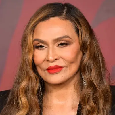 Tina Knowles wears her golden brown color in long waves with a deep center part