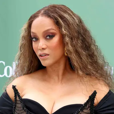 Tyra Banks wears a golden brown wig in soft brushed out waves with a center part
