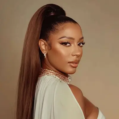 Victoria Monet wearing her golden brown hair in a high snatched ponytail
