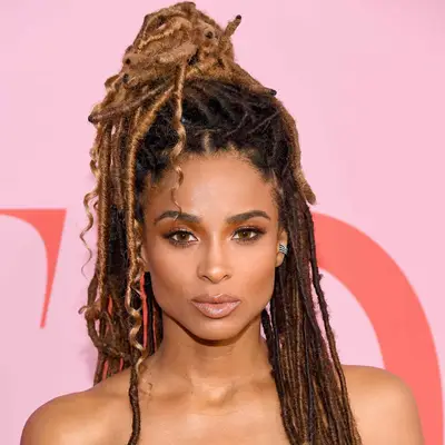 Ciara wears golden brown locs in a half up top knot