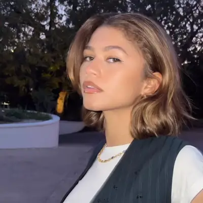 Zendaya wears a bob hairstyle with dark brown roots and honey and caramel highlights