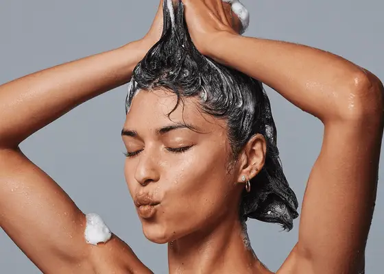 Woman applying shampoo through her short brown hair