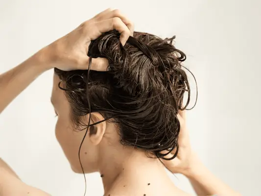 A woman washing her hair and scrubbing her scalp