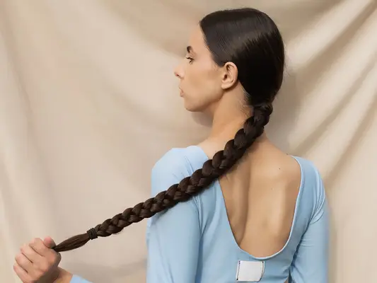 Woman in blue T-shirt holds long black ponytail
