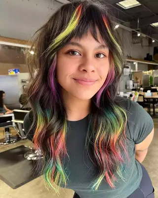 woman wearing a black turtleneck with lavender peekaboo highlights on a short bleach blonde bob 