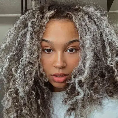 Woman with brunette natural curls with silver-blonde highlights