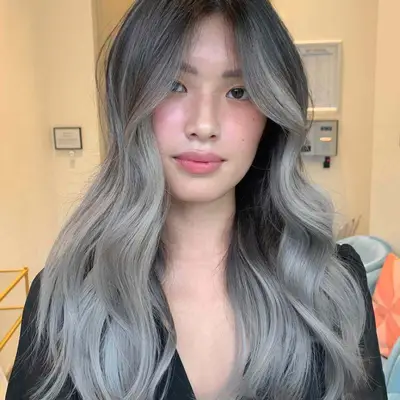 Woman with silver-toned balayage ombre hair with dark roots and blonde ends
