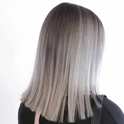 Back view of medium-length silver balayage hair with dark roots