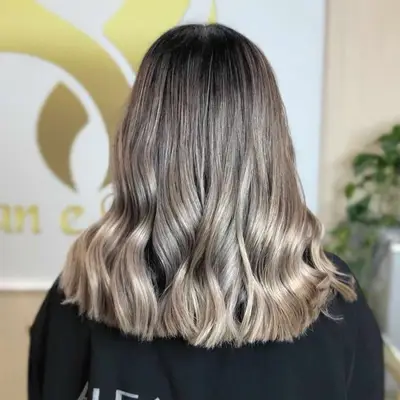 Back view of mid-length brown to blonde ombre hair with ashy silver balayage highlights