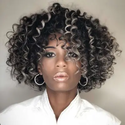 Woman with naturally curly dark hair with scattered silver highlights