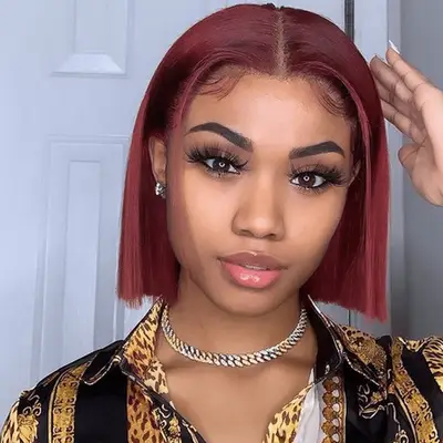 A masculine person with burgundy hair and baby bangs