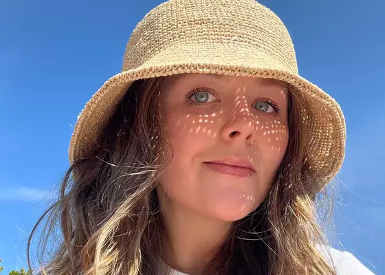 byrdie editor holly rhue wearing woven sun hat 