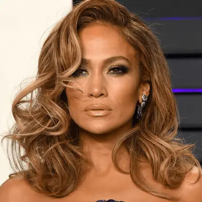 Jennifer Lopez voluminous honey-blonde curls, smoky eye, and nude lipstick