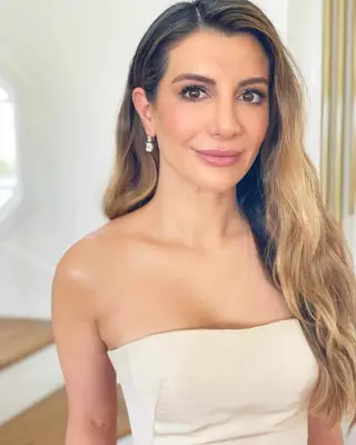 Nasim Pedrad with darker roots and a warm dirt blonde hair color on the lengths